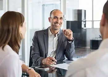 Mature financial agent in a meeting with a young couple, demonstrating professional vCTO consulting services.